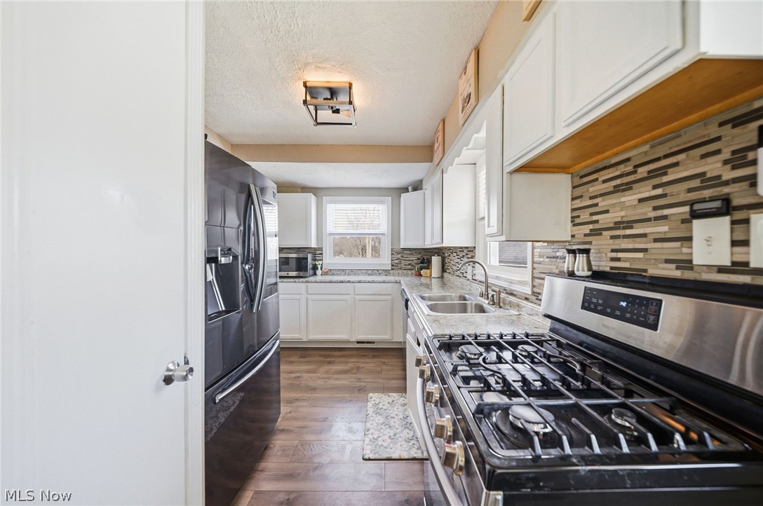 3905 Kent Road Stow, OH 44224 - Photo 19 of 45 Kitchen with stainless steel appliances, white cabinets, decorative backsplash, dark wood-type flooring, and a textured ceiling