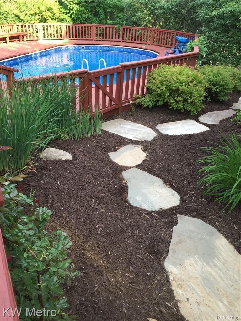 2211 West Wardlow Road Highland, MI 48357 - Photo 14 of 53 Side entrance to pool during summer with beautiful landscaping.