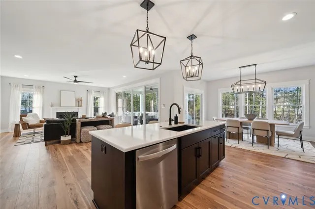 a open kitchen with stainless steel appliances granite countertop a sink dishwasher a stove a dining table and chairs with wooden floor