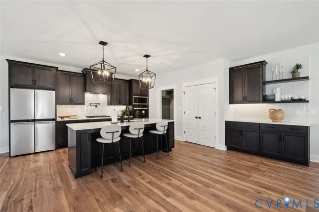 a large kitchen with a center island wooden floor stainless steel appliances and cabinets