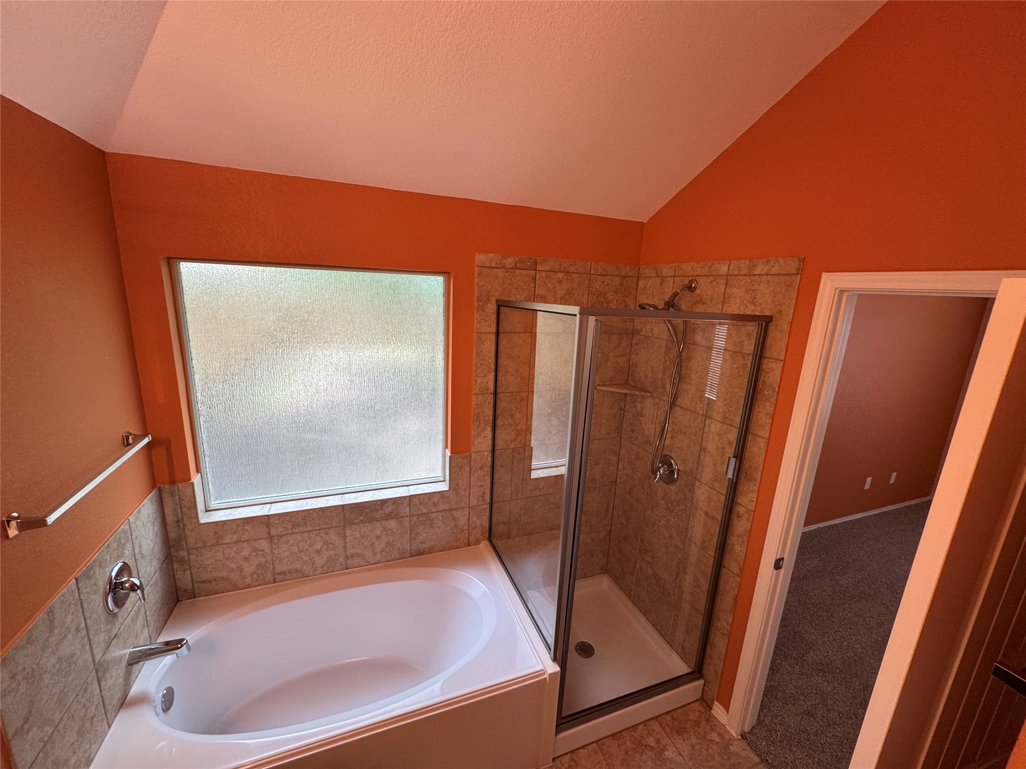 112 Eagle Owl Loop Leander, TX 78641 - Photo 11 of 34 Bathroom featuring a corner soaking tub, a separate glass-enclosed shower with tile surround, a frosted window, and a vaulted ceiling