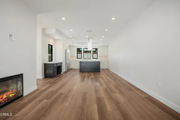 a view of empty room with kitchen and fireplace