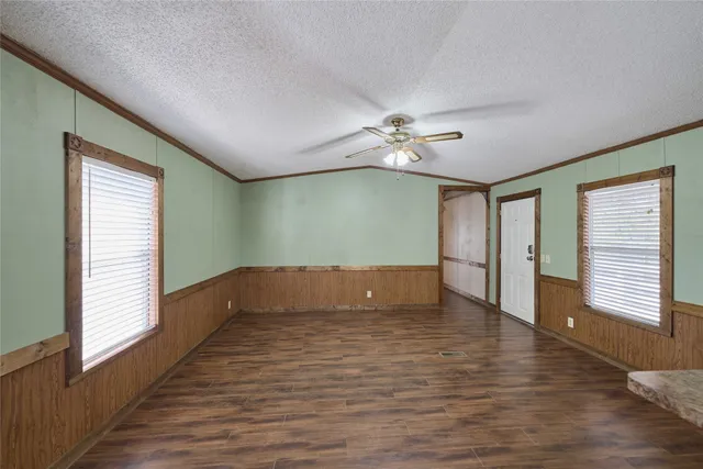 a view of empty room with wooden floor and fan