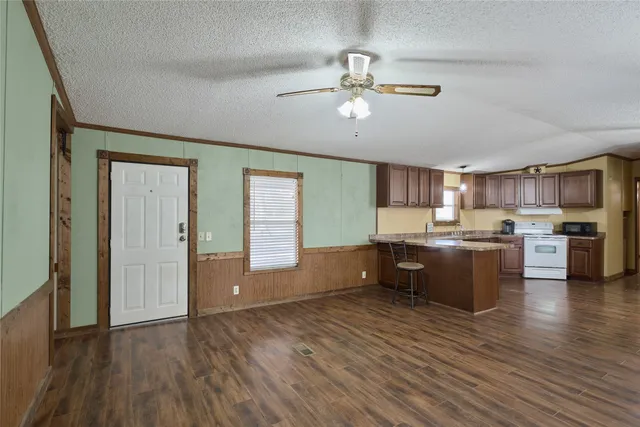 a room with stainless steel appliances kitchen island granite countertop wooden floors and view living room