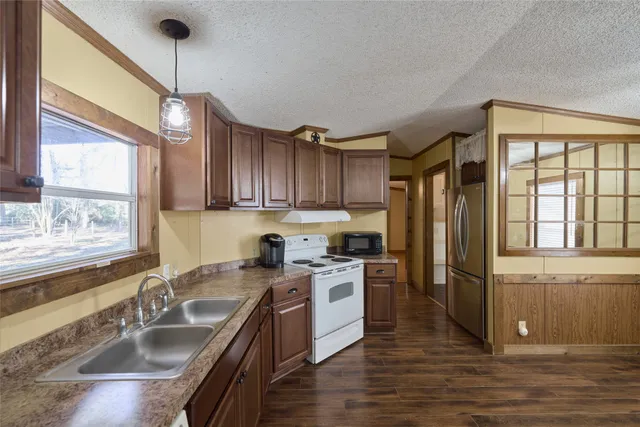 a kitchen with stainless steel appliances granite countertop a sink a stove and a refrigerator