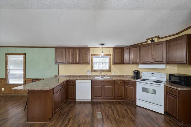 a kitchen with a sink cabinets wooden floor and stainless steel appliances