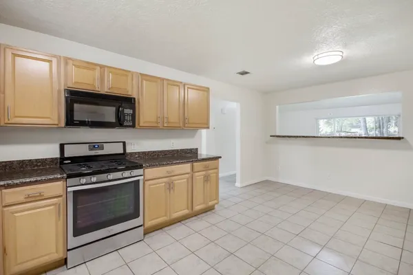 a kitchen with granite countertop white cabinets stainless steel appliances and a window