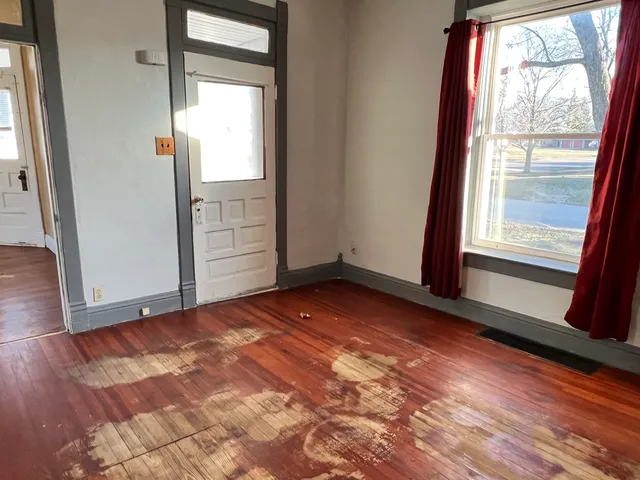 a view of an empty room with wooden floor and a window