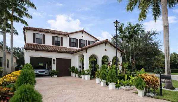 a view of a white house with a big yard and potted plants