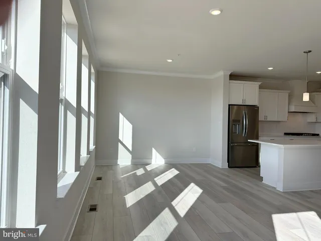a view of a kitchen with kitchen island wooden floors appliances and furniture