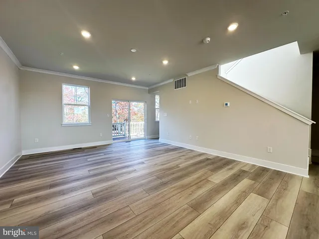 a view of a hallway with wooden floor and a bathroom