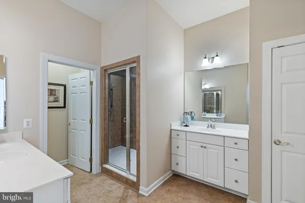 a spacious bathroom with a double vanity sink a large mirror and a bathtub