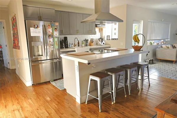 a kitchen with stainless steel appliances granite countertop a refrigerator a sink a stove and white cabinets with wooden floor