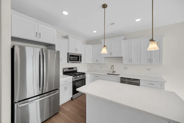 a large kitchen with stainless steel appliances a refrigerator a stove a sink and a center island