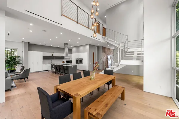 a living room with stainless steel appliances furniture a rug and a kitchen view