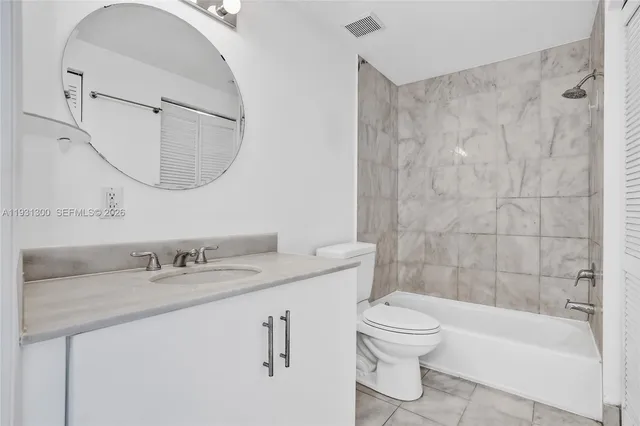 a bathroom with a granite countertop sink a toilet and a mirror