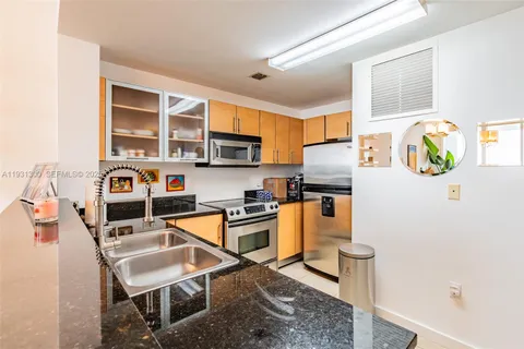 a kitchen with stainless steel appliances granite countertop a stove top oven a sink a counter space and cabinets