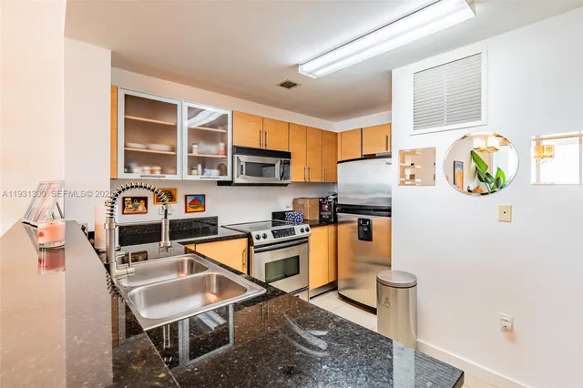 a kitchen with stainless steel appliances granite countertop a stove top oven a sink a counter space and cabinets
