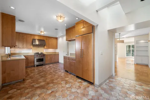 a kitchen with stainless steel appliances granite countertop a refrigerator a sink a stove and a refrigerator