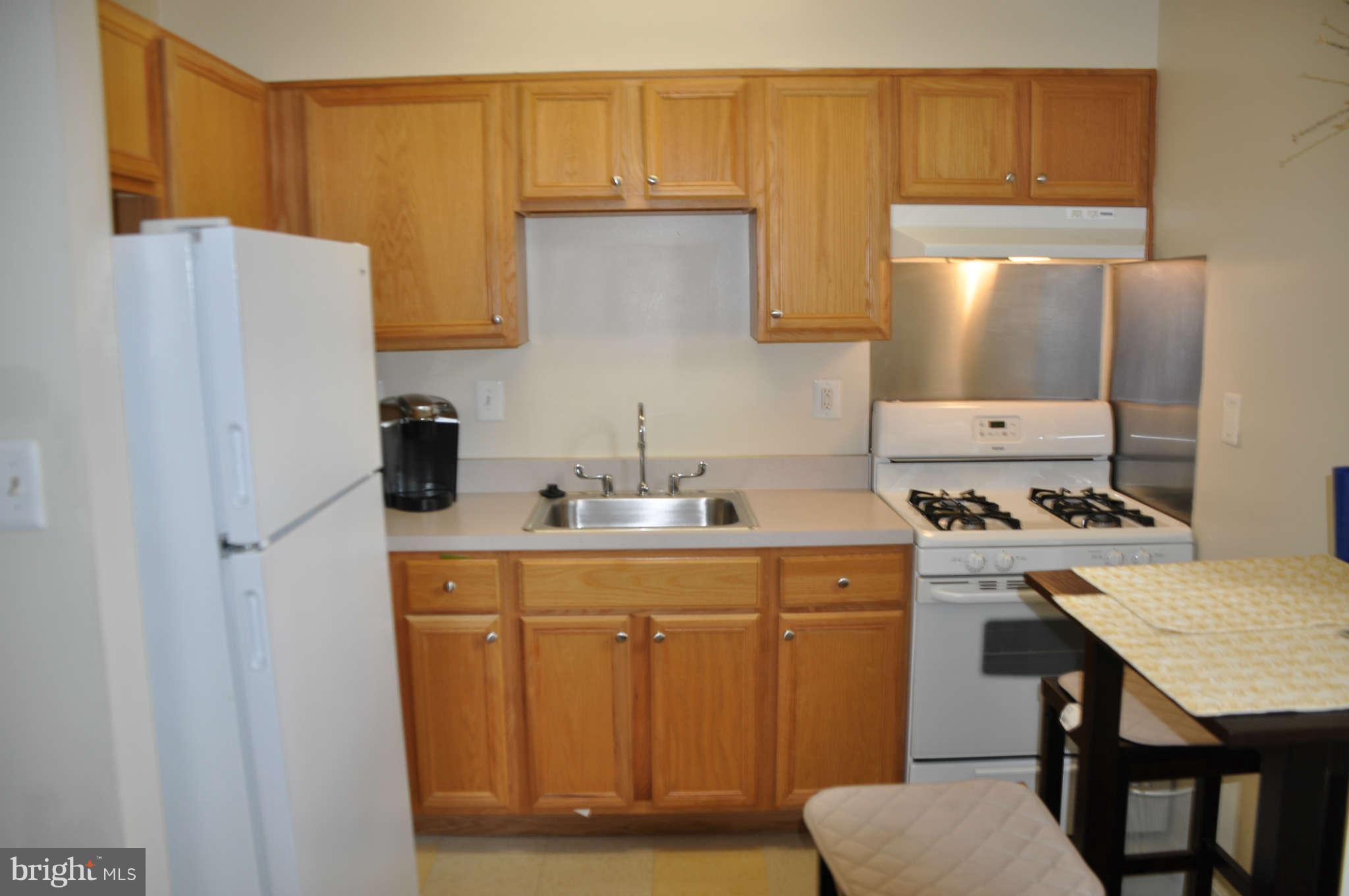 1440 W Street Northwest, Unit 406 Washington, DC 20009 - Photo 3 of 12 a kitchen with stainless steel appliances a stove a sink a refrigerator and white cabinets