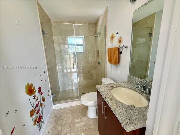 a bathroom with a granite countertop sink a toilet and shower
