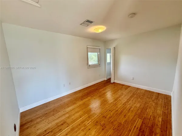a view of empty room with wooden floor and fan