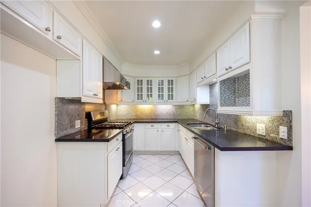 a kitchen with granite countertop a sink a stove and cabinets