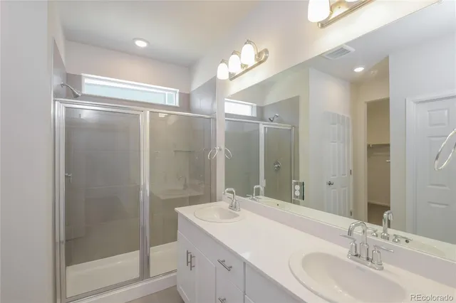 a bathroom with a double vanity sink mirror and shower