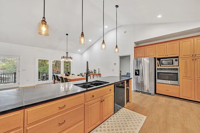 a kitchen with stainless steel appliances granite countertop a sink a stove and a wooden floor