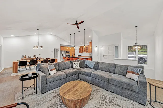 a living room with furniture kitchen view and a chandelier