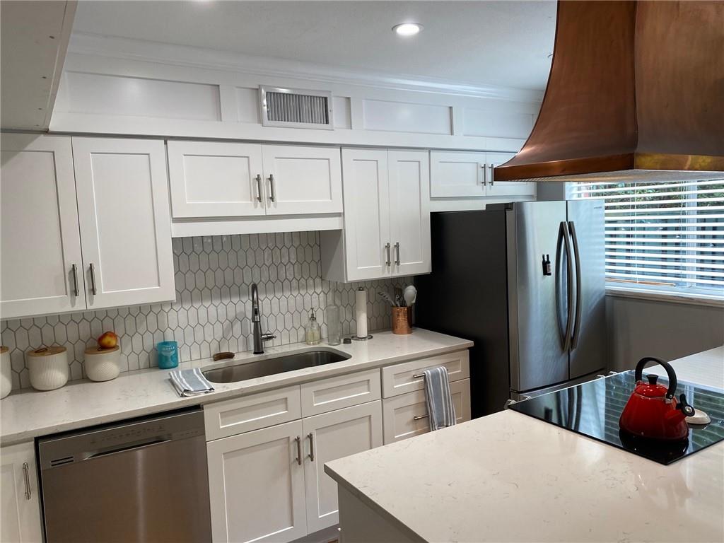 a kitchen with stainless steel appliances a sink stove refrigerator and cabinets