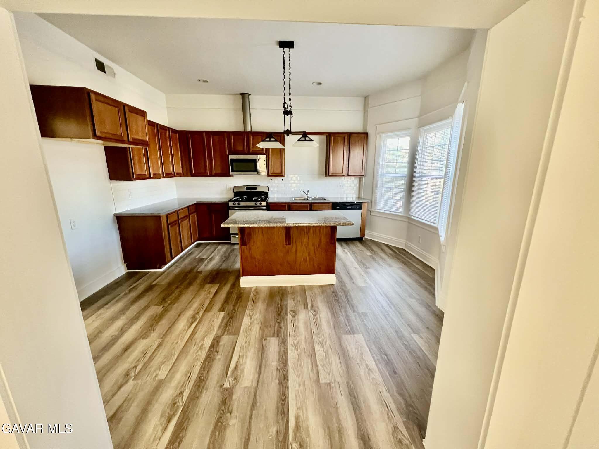 2702 19th Street Bakersfield, CA 93301 - Photo 8 of 21 a kitchen with wooden floors and stainless steel appliances