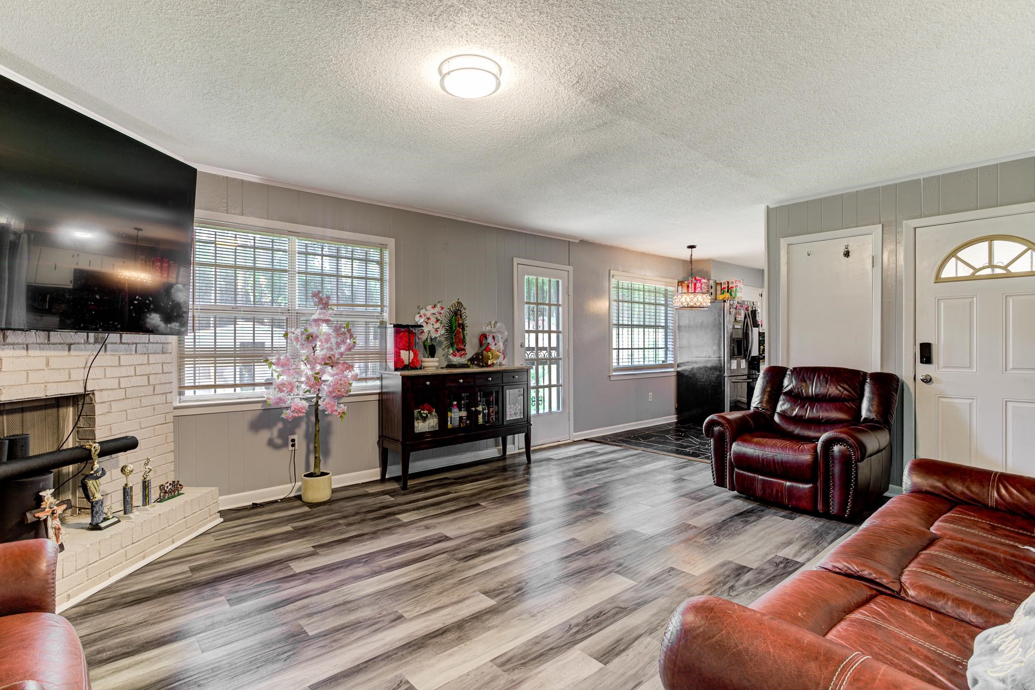 6044 Raintree Drive Memphis, TN 38115 - Photo 7 of 22 Living area featuring wood finished floors, a textured ceiling, and a fireplace