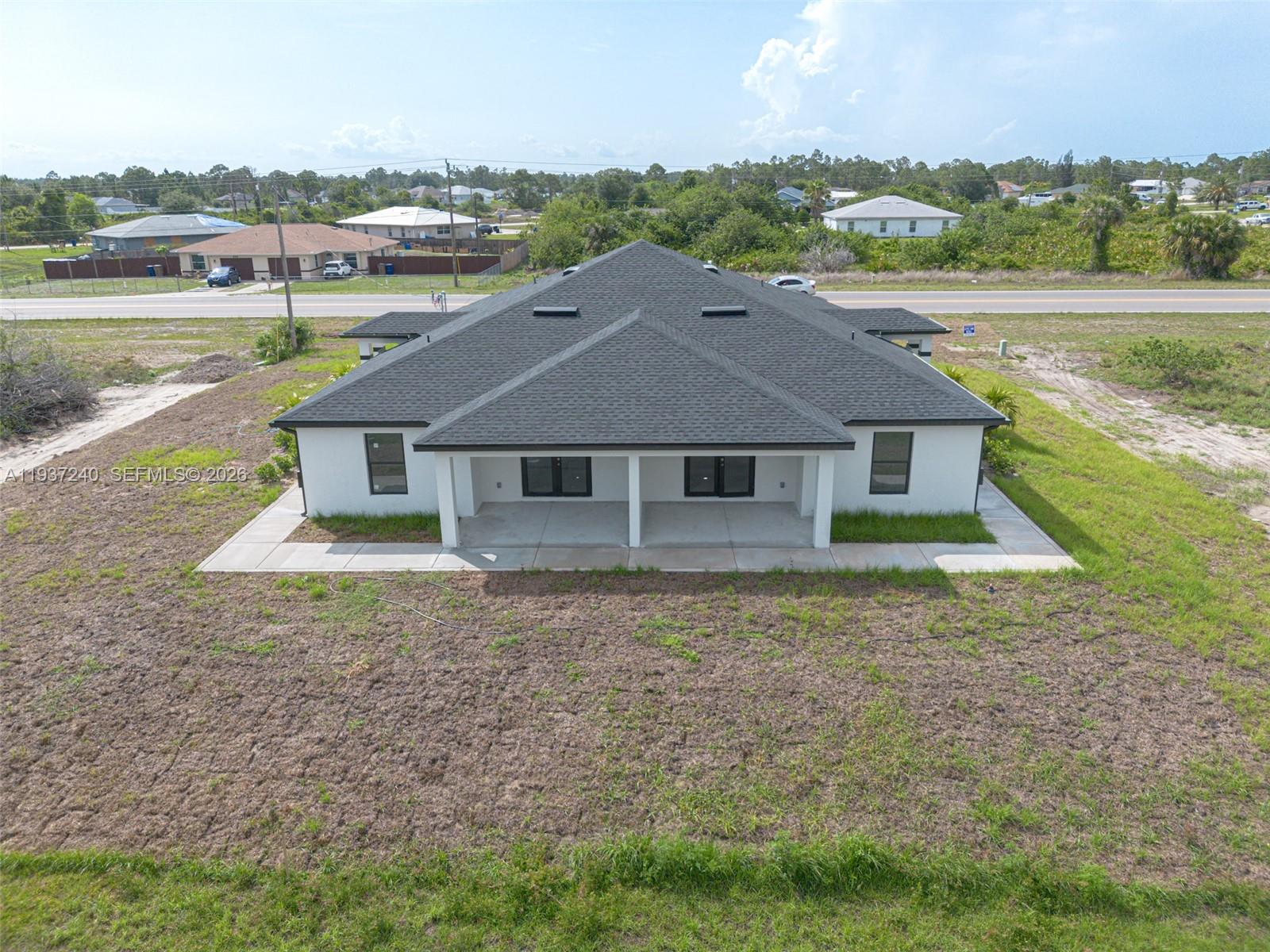 842-844 Alabama Road South Lehigh Acres, FL 33974 - Photo 13 of 40 a aerial view of a house next to a yard with plants and large trees