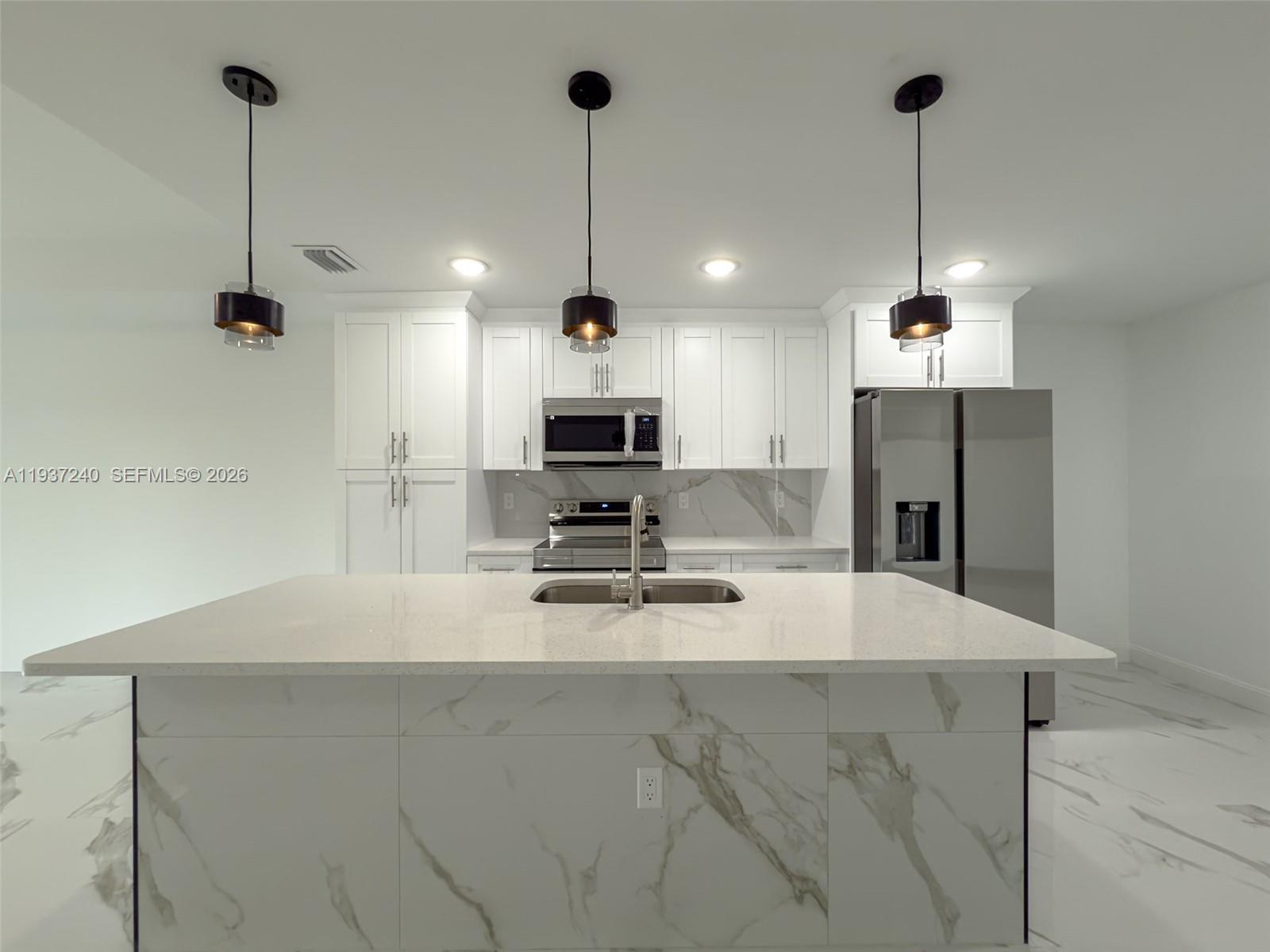 842-844 Alabama Road South Lehigh Acres, FL 33974 - Photo 37 of 40 a kitchen with kitchen island a counter top space appliances and a chandelier