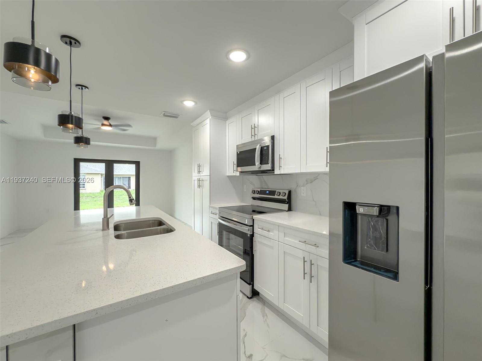 842-844 Alabama Road South Lehigh Acres, FL 33974 - Photo 38 of 40 a kitchen with a refrigerator a sink dishwasher a stove and white cabinets with wooden floor