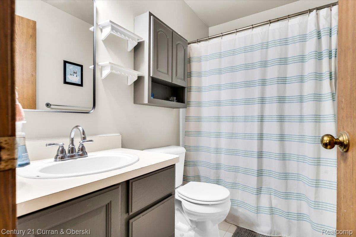 21439 Hall Road Trenton, MI 48183 - Photo 21 of 35 Bathroom featuring a vanity with an integrated sink and chrome faucet, under-sink cabinetry, and an overhead storage cabinet