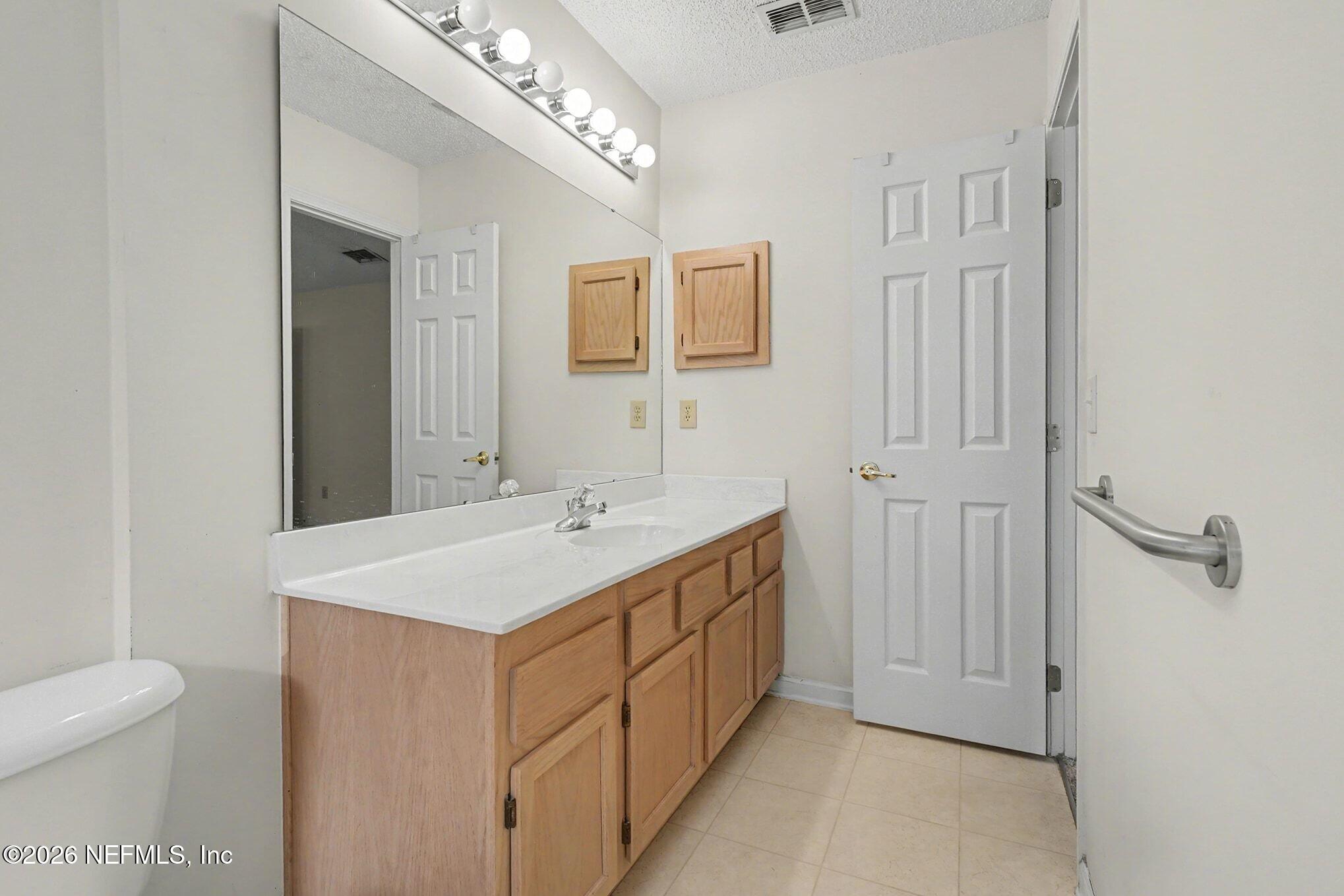 11958 Swooping Willow Road Jacksonville, FL 32223 - Photo 13 of 31 a bathroom with a sink a toilet and mirror