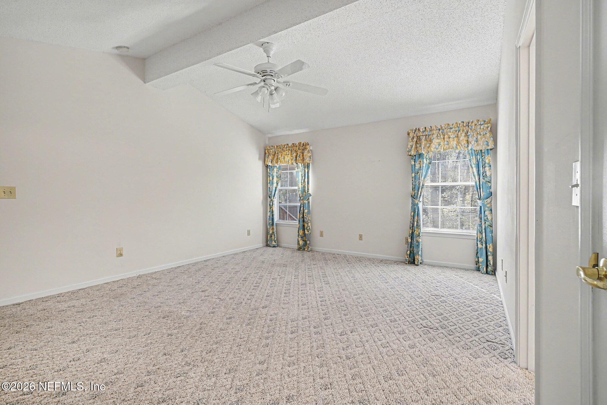 11958 Swooping Willow Road Jacksonville, FL 32223 - Photo 16 of 31 an empty room with chandelier fan and windows