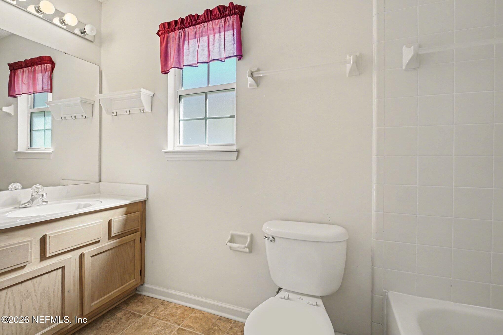 11958 Swooping Willow Road Jacksonville, FL 32223 - Photo 22 of 31 a bathroom with a toilet sink vanity and mirror