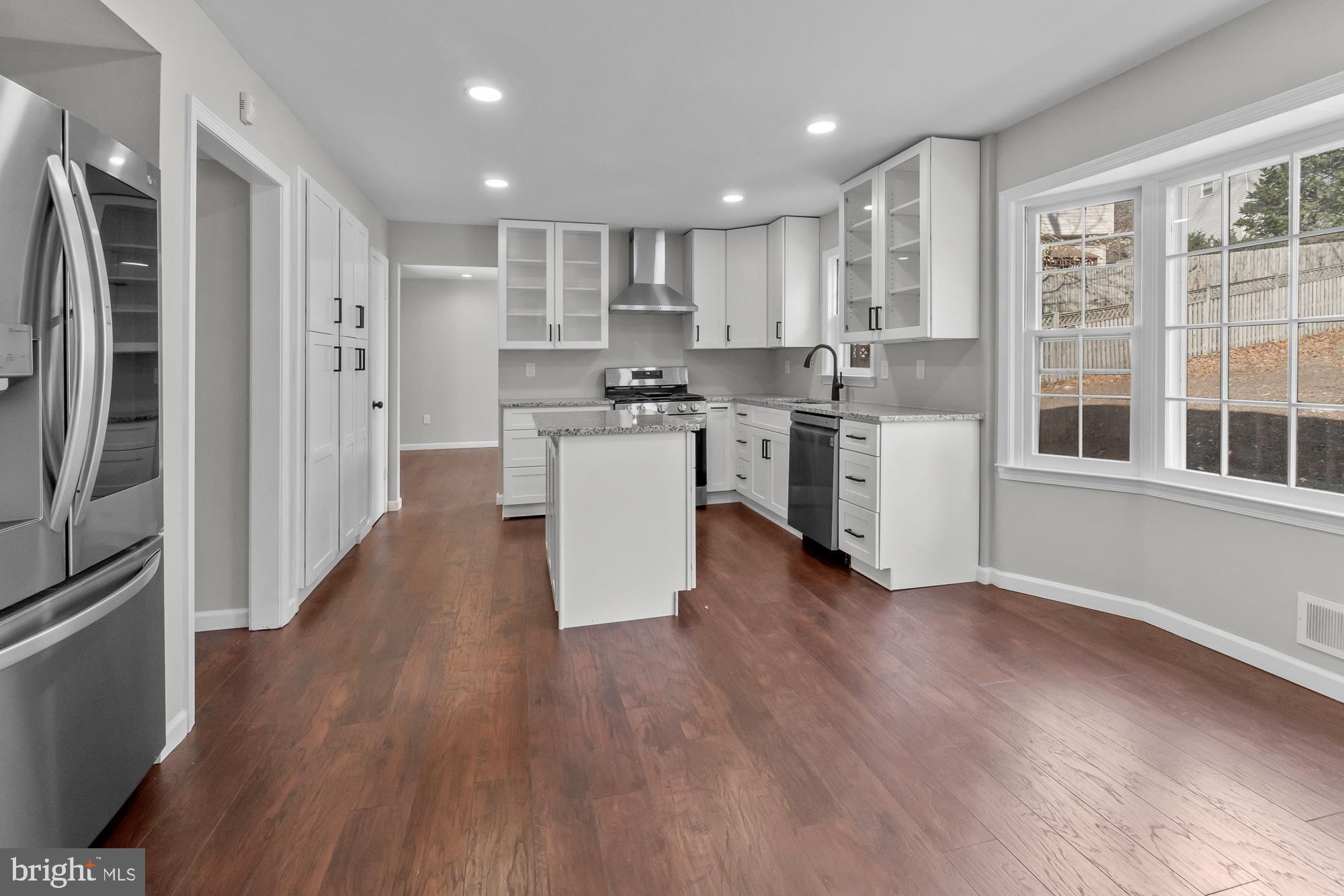 12539 Heurich Road Silver Spring, MD 20902 - Photo 9 of 46 a kitchen with stainless steel appliances granite countertop a refrigerator a sink dishwasher a stove and white countertops with wooden floor