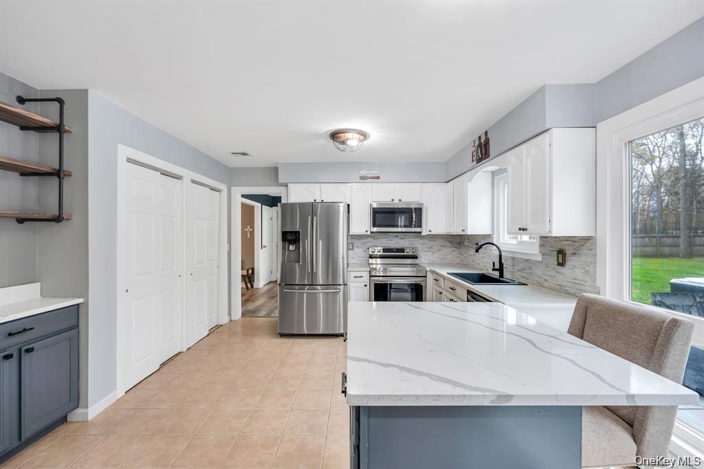10 Ramblewood Road Ridge, NY 11961 - Photo 16 of 39 a living room with stainless steel appliances a refrigerator a stove a sink a dining table and chairs