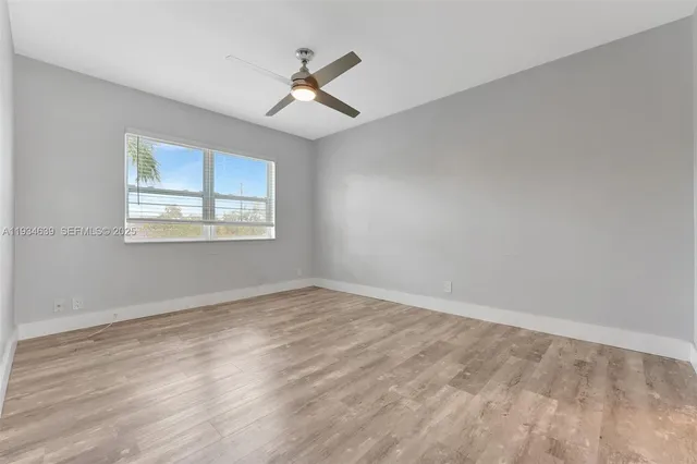 a view of an empty room with a window and wooden floor