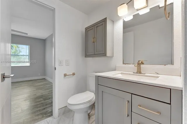 a bathroom with a granite countertop sink a toilet and a mirror