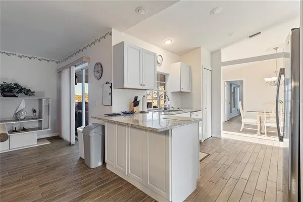 a kitchen with stainless steel appliances granite countertop a refrigerator a sink dishwasher and white cabinets with wooden floor