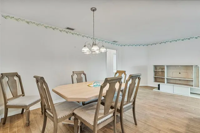 a view of a dining room with furniture a chandelier and wooden floor