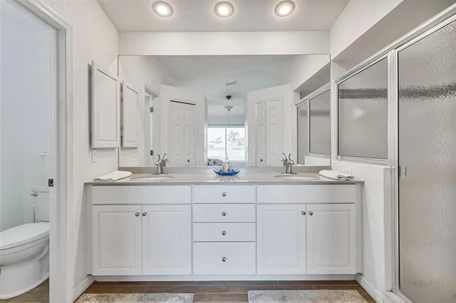 a bathroom with a double vanity sink a toilet and a mirror