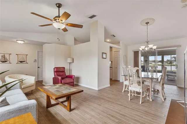 a dining room with wooden floor a chandelier a glass table and chairs