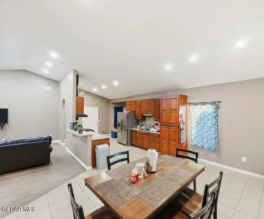a living room with stainless steel appliances furniture a rug and a kitchen view