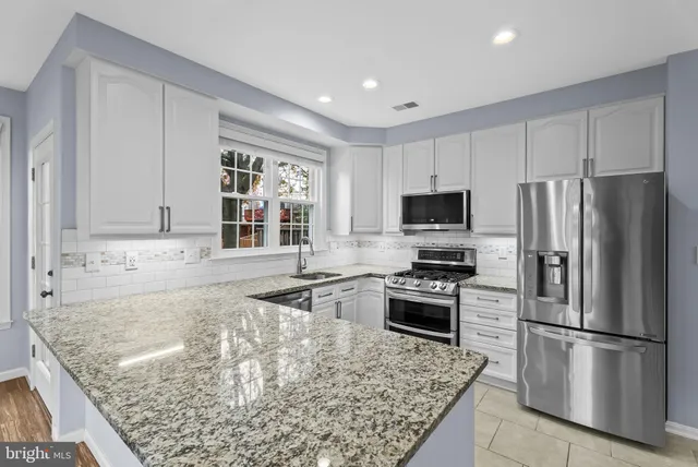 a kitchen with granite countertop a refrigerator stove and oven